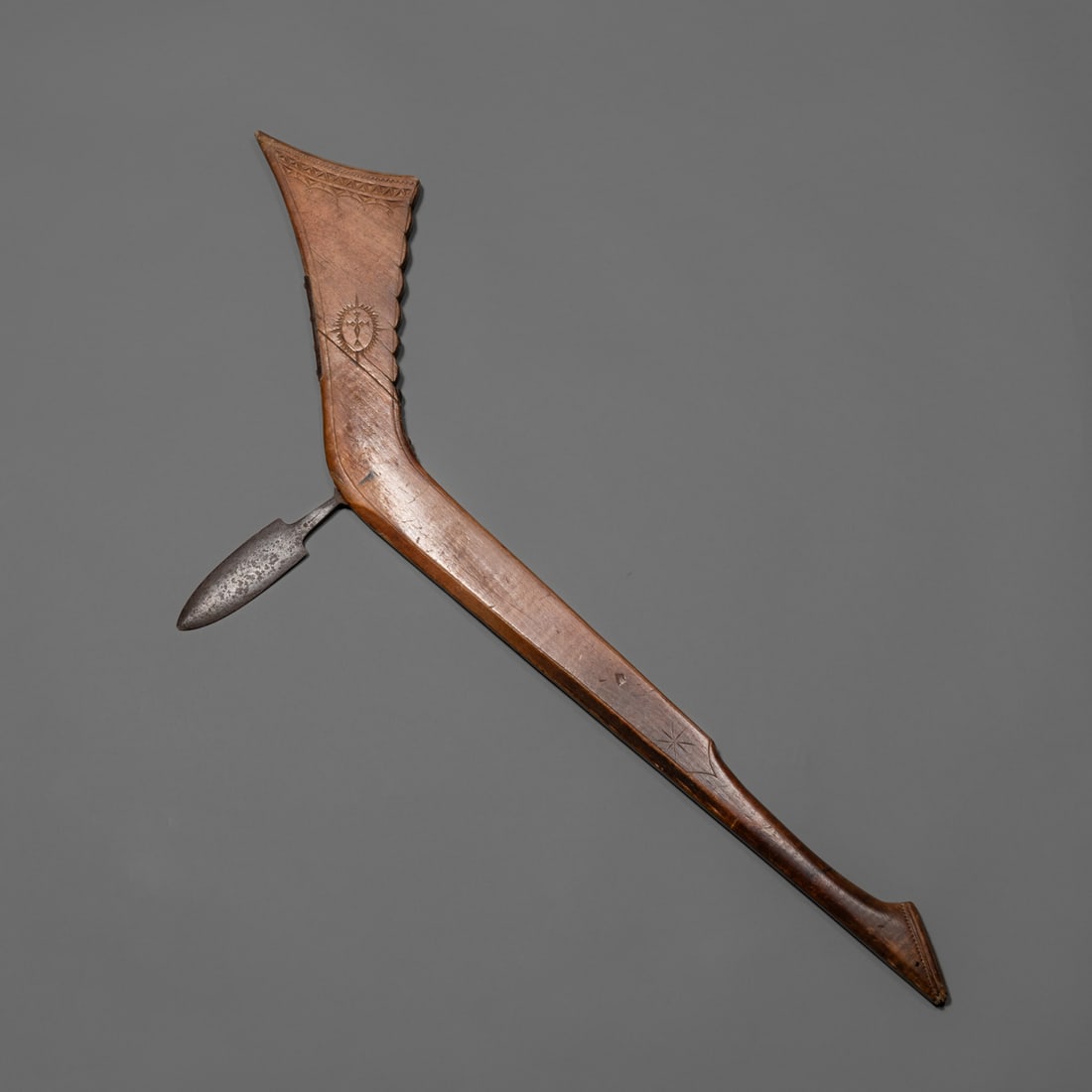 A Western Great Lakes/Eastern Minnesota Sioux Gun stock club: Mid 19th century, fine chipped and incised carving, traces of pigment, sun burst with cross design reminiscent of early trade silver, a raw iron, steel blade, includes a custom-made wall display