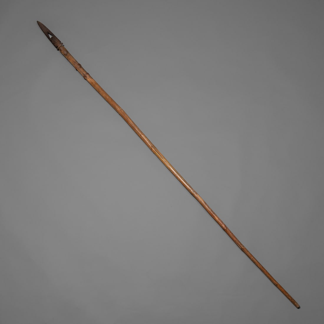 A Northern Plains lance: The long cylindrical wood shaft wrapped with cords near the upper portion, the blade featuring a holed arrow design element. Rich, warm patina throughout. Lg. 78 in.Provenance: Mike Rounig.