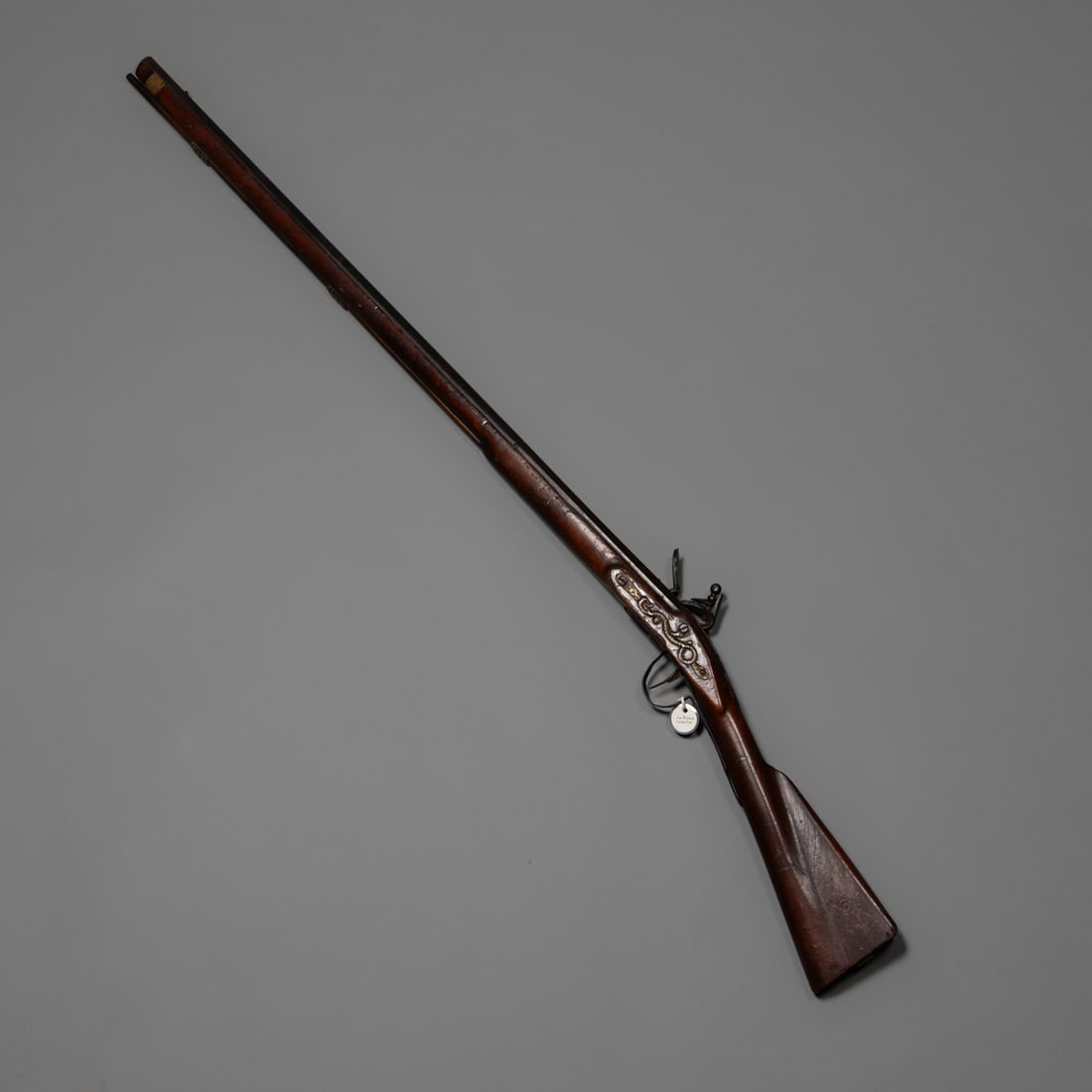 A Fur trade era serpent side plate trade gun: An early trade gun featuring a serpent-form side plate. The long barrel and full walnut stock display rich age patina, with evident handling wear from extended use. Iron and brass mounts show