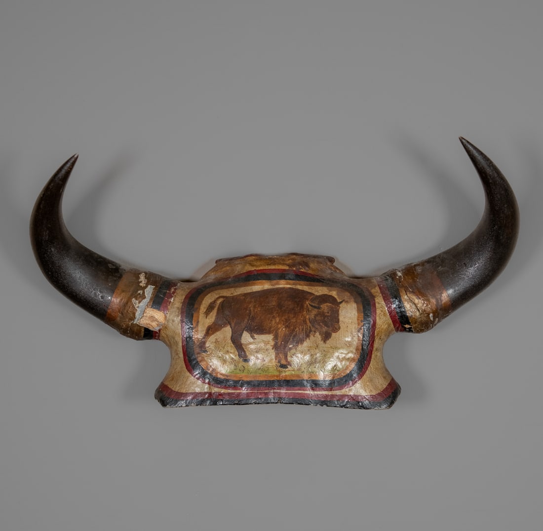 A folk-art buffalo horn mount: Featuring a painted image of a buffalo in profile across the skull cap. The composition is framed with concentric bands of red, black, and ochre pigment, creating a vivid border around the central