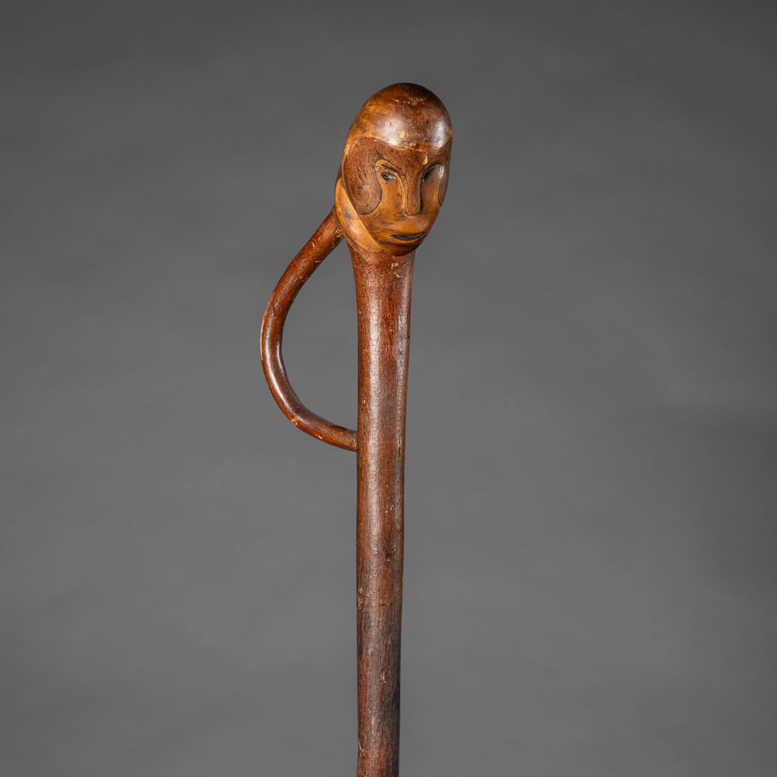 A Woodlands Native effigy staff with human face: A rare, mid 19th century hand carved hardwood staff featuring a finely modeled human effigy face on the staff. The face with incised expressive features above the long staff and handle. Dark toned
