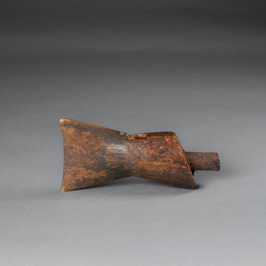 A Northwest Coast fish fluke powder horn: 19th century, hand-carved from a single piece of wood in the form of a fish fluke, with part of a gun barrel at the flat end, and pierced at the top side. The wood is deeply patinated and aged. Lg. 7