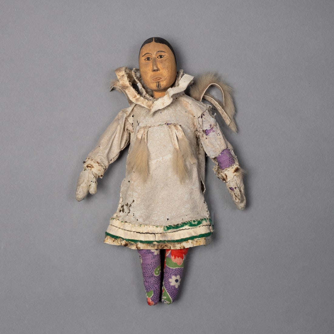 An Eskimo doll: Alaska, circa 1900, the cloth doll with hide coat and gloves with fur trim, and painted wood head, (insect damage to the garments). Ht. 7 3/4 in. Provenance: Private collection, Albuquerque, NM; Tad