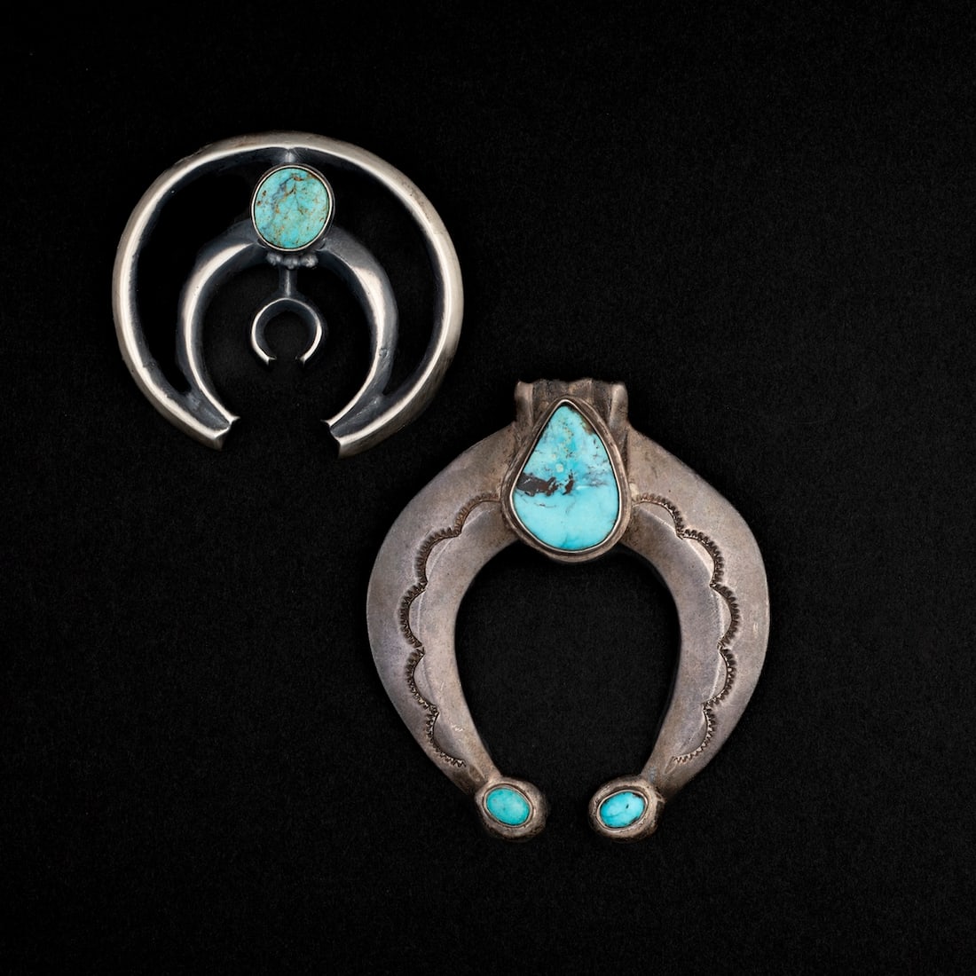Two Navajo (Diné) Silver and turquoise naja: An unusual, oversized silver naja with three turquoise settings and stamp work, the smaller two-wire nada with a single turquoise setting, three silver balls and small horseshoe element, marked “JL
