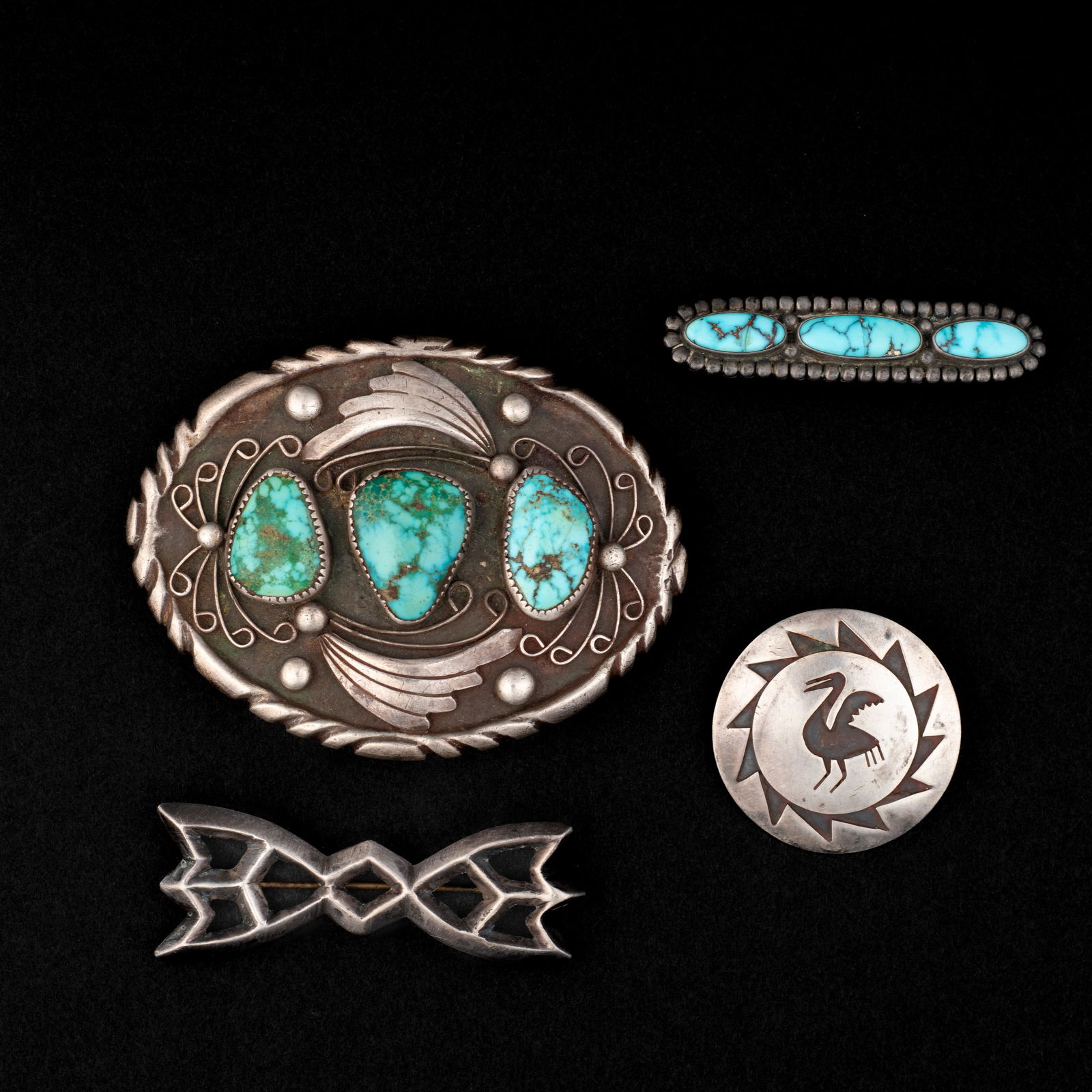 A Southwest belt buckle and three pins: The heavy oval silver plaque with silver appliqué and three turquoise settings, with three pins. Size of buckle 2 1/2 x 3 3/8, dia. 1 1/2, lg. 2 1/2 and 2 3/8 in.