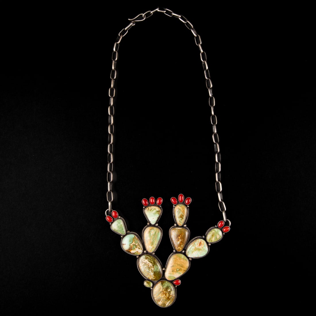 An Annie Hoskie silver and turquoise necklace: The silver chain supports a large cactus form with turquoise and coral settings, signed "Annie Hoskie," and marked "Sterling." Lg. of necklace untied 23, pendant size 4 x 4 1/2 in. Gross weight approx