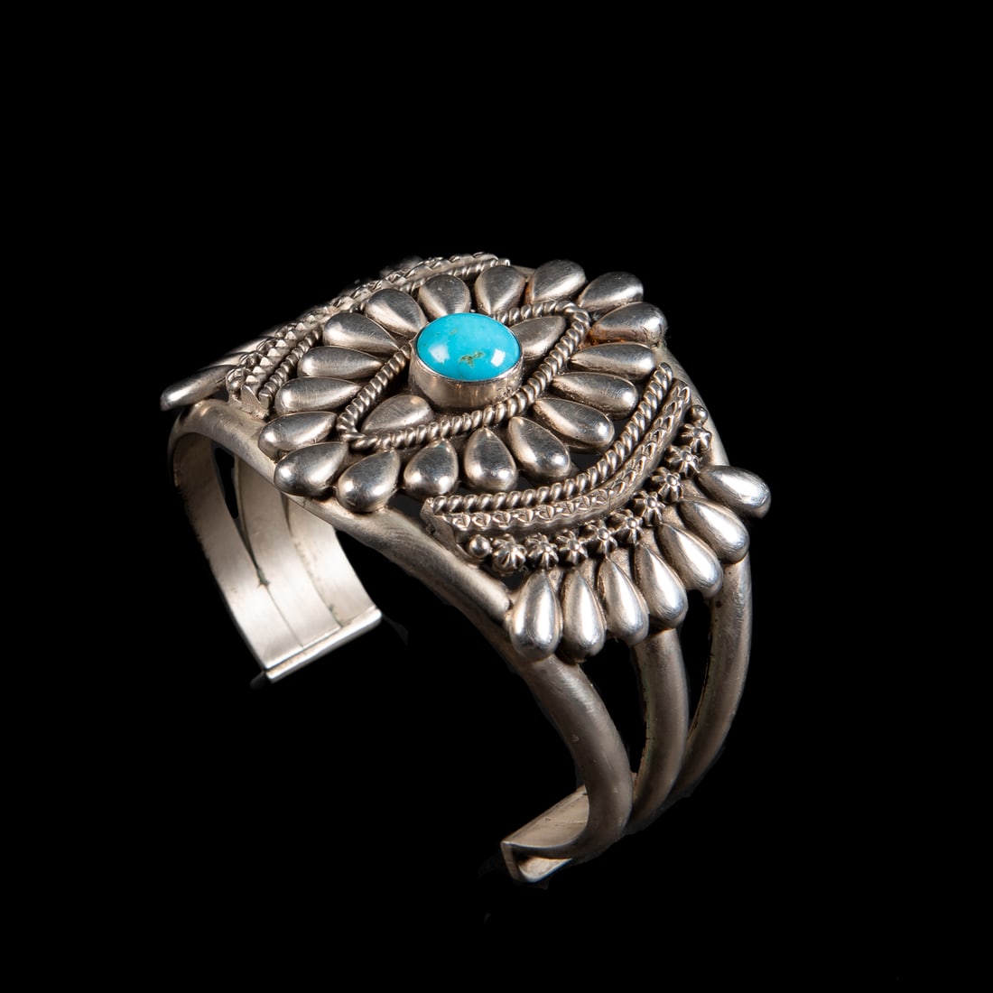 A Thomas Jim silver and turquoise cuff bracelet: The three-wire Sterling cuff with silver teardrop, star and ropework with a single turquoise setting, signed "T Jim," and marked "Sterling." Total interior circumference (including gap) 6 1/4, wd. 2,