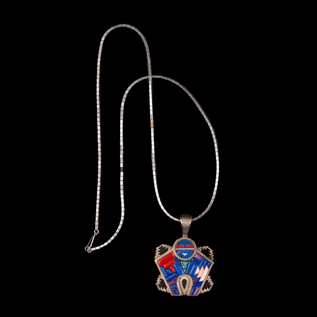 A Larry Castillo silver and inlay necklace: The silver chain with a silver naja-shaped pendant with turquoise, coral and lapis inlay, marked "L C" and "Sterling." Lg. of necklace 28, size of pendant 2 3/4 x 2 in. with bail. Gross weight
