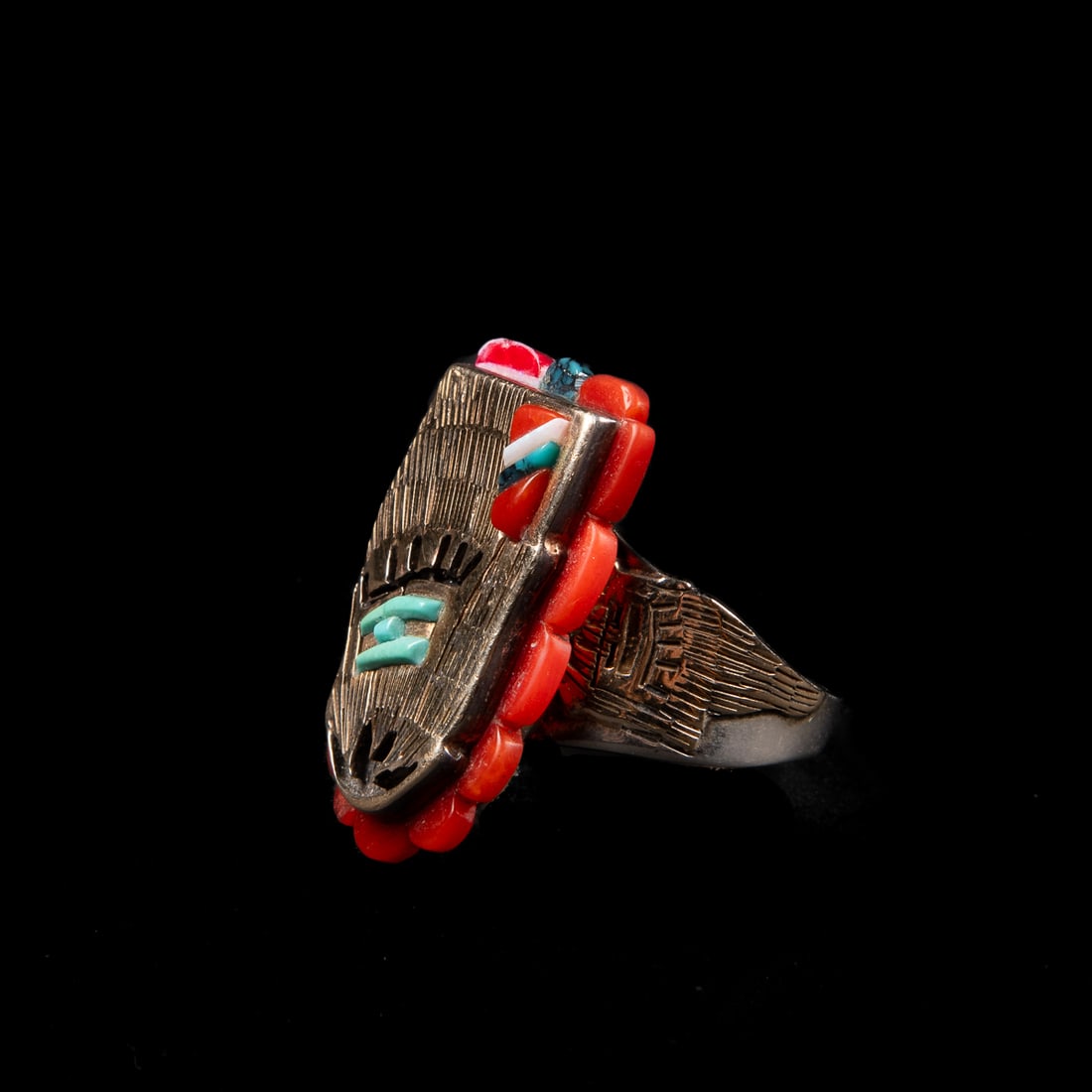 A Wilbert Manning gold and silver ring: The silver and 14k gold ring with turquoise, coral and jet inlay, marked with "WM," and "Sterling 14K." Ring size 10, 1 1/8 x 3/4 in. Gross weight 20g.
