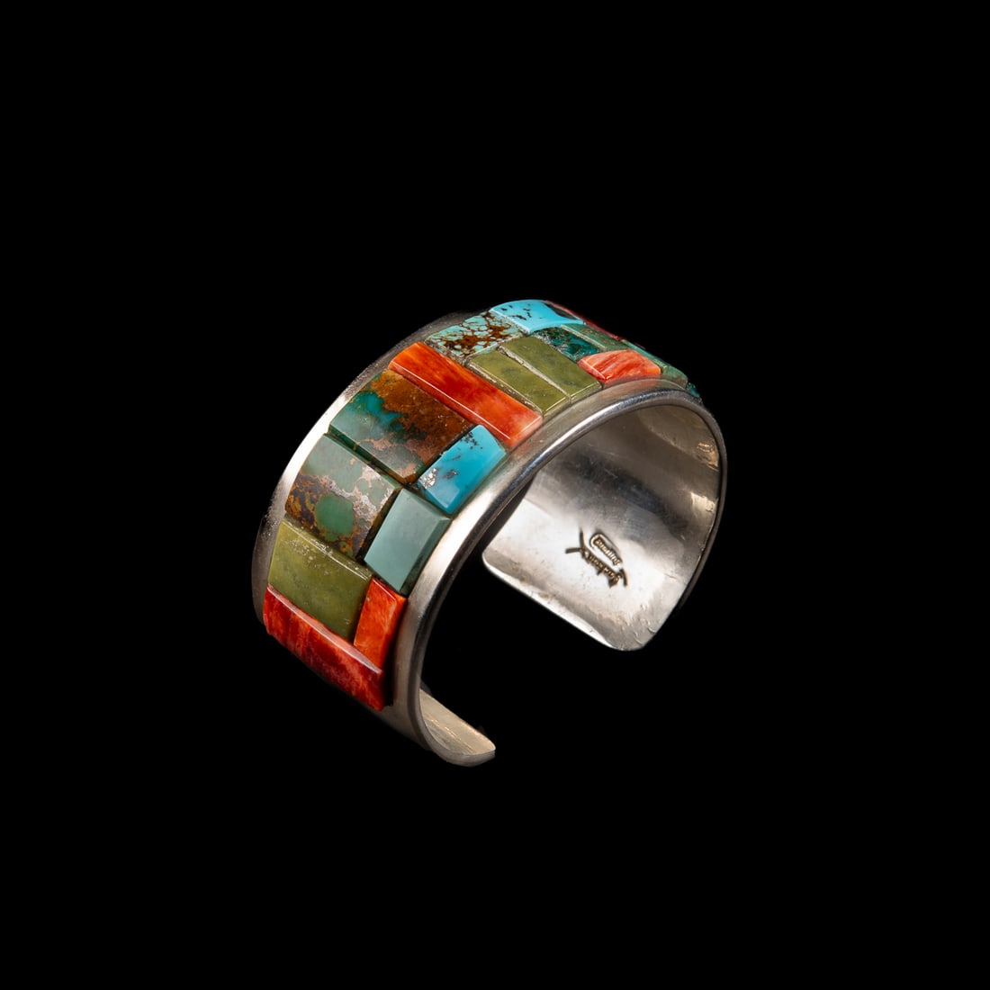 A Tommy Jackson silver and turquoise cuff bracelet: The wide Sterling silver cuff with turquoise and spiny oyster cobblestone inlay, signed "Jackson," and marked "Sterling." Total interior circumference (including gap) 6 1/2, wd. 1 1/8, gap 1 in.