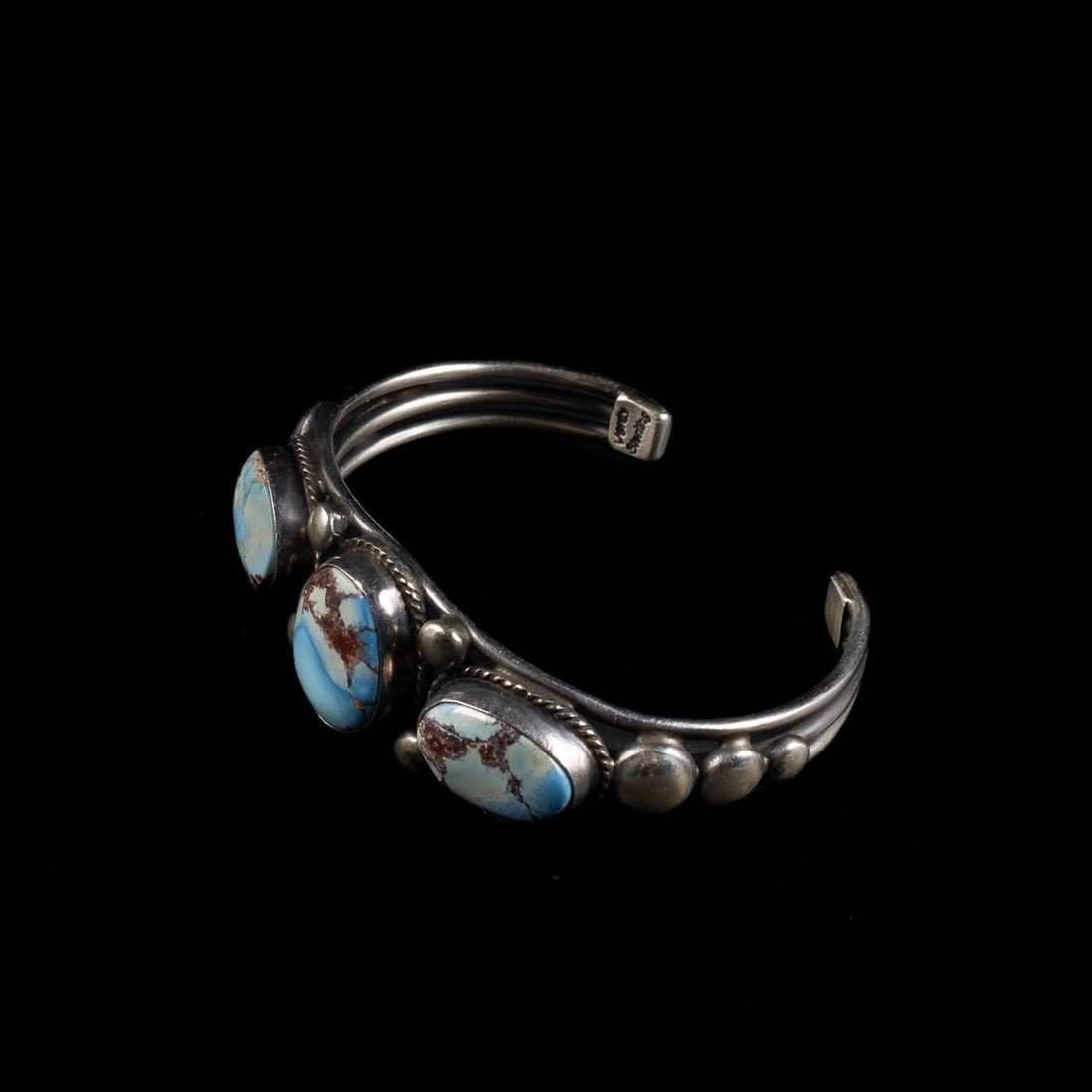 A Verdy Jake silver and turquoise bracelet: The three-wire cuff with three Golden Hill turquoise settings surrounded by rope work and silver balls, signed "Verdy" and marked "Sterling." Total interior circumference (including gap) 6 1/2, wd.