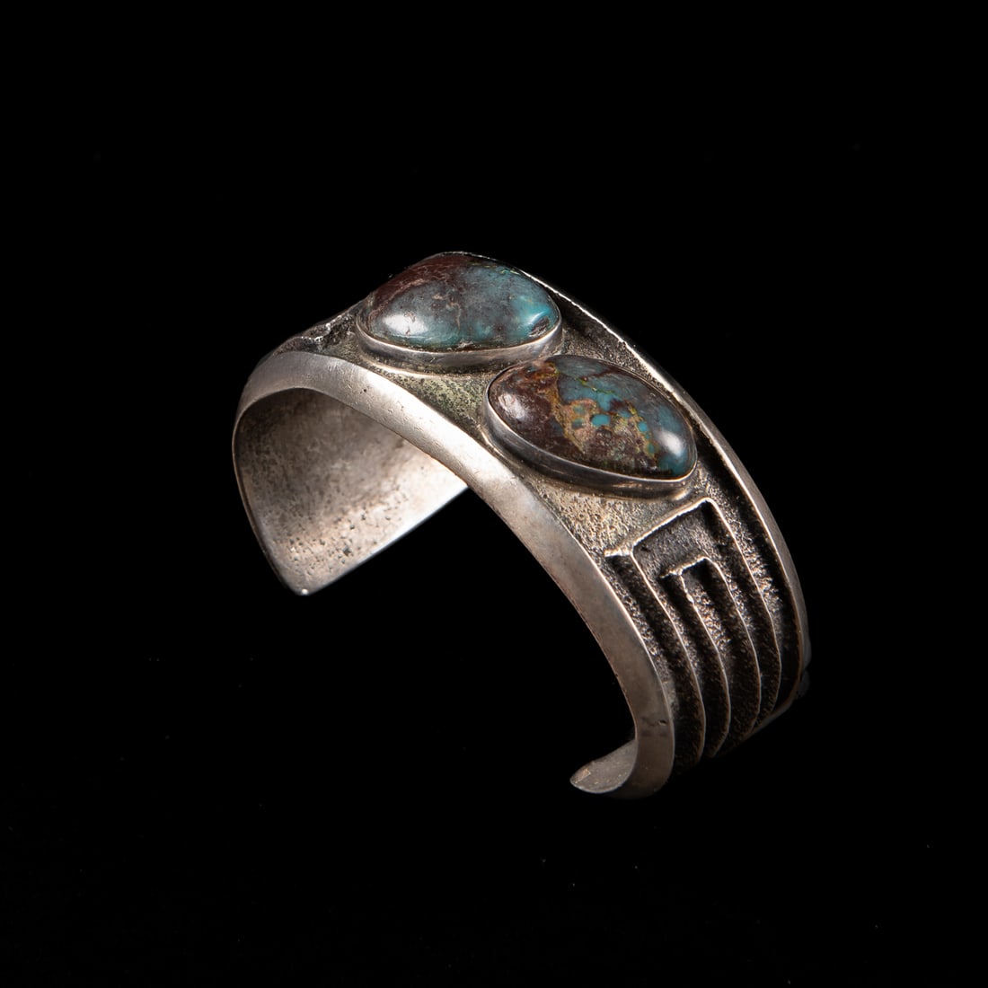 A John Hornbeck silver and turquoise cuff bracelet: John Hornbeck (Anglo), the tufa cast silver cuff with two Bisbee turquoise settings, stamped with the Hornbech hoof markings. Total interior circumference (including gap) 6 1/4, wd. 1 1/4, gap 1 1/2 i