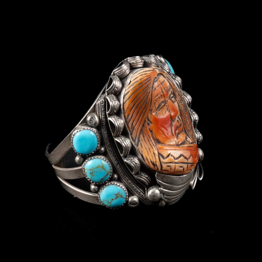 A Francisco Gomez cuff bracelet: Francisco Gomez (Spanish), the Sterling silver three-wire cuff with six turquoise settings between a carved portrait of a Native American, marked "G" and "Sterling." Total interior circumference (incl