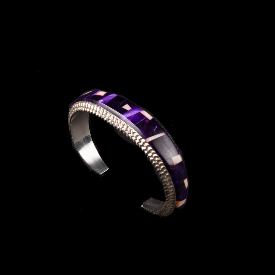An Alvin Yellowhorse cuff bracelet: The silver bracelet with flush inlay sugilite and coral, signed "Alvin Yellowhorse." Total interior circumference (including gap) 6 1/2, wd. 5/8, gap 1 in. Gross weight approximately 39g.