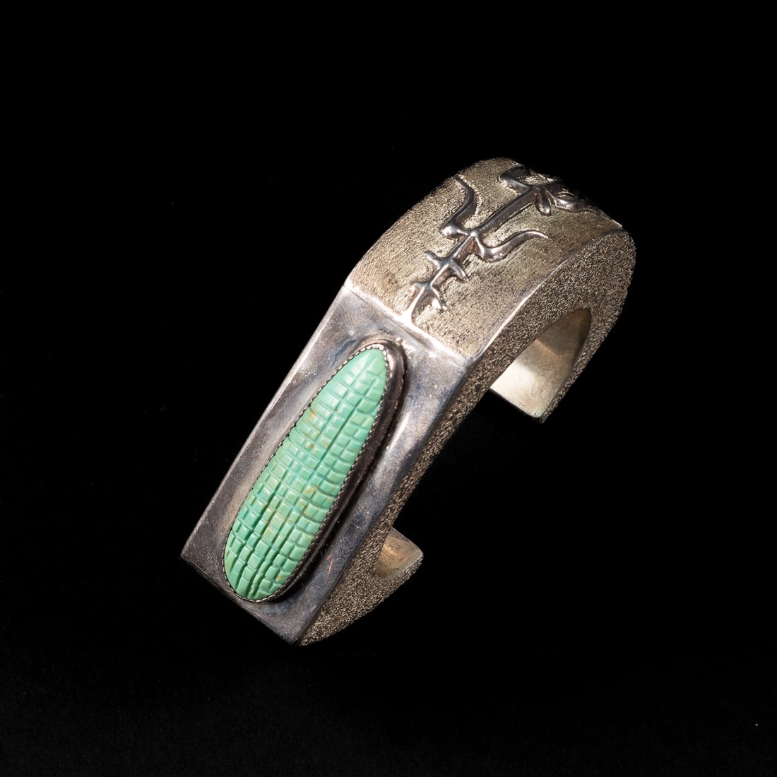 A Henry Rosetta cuff bracelet: The Sterling silver sculptural bracelet with a free form silver corn plant around half the bracelet, with a turquoise ear of corn on the other, marked "HR" and "Sterling." Total interior circumference