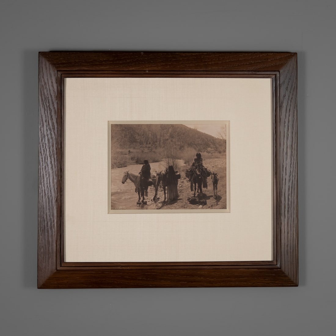 An Edward Curtis Platinum photograph: Edward S. Curtis(American, 1868-1952). At the Ford - Apache, 1903, platinum photograph, signed "Curtis," lower right, embossed and printed copyright 1903, framed. Size of photo 5 3/4 x 7 1/2, size of