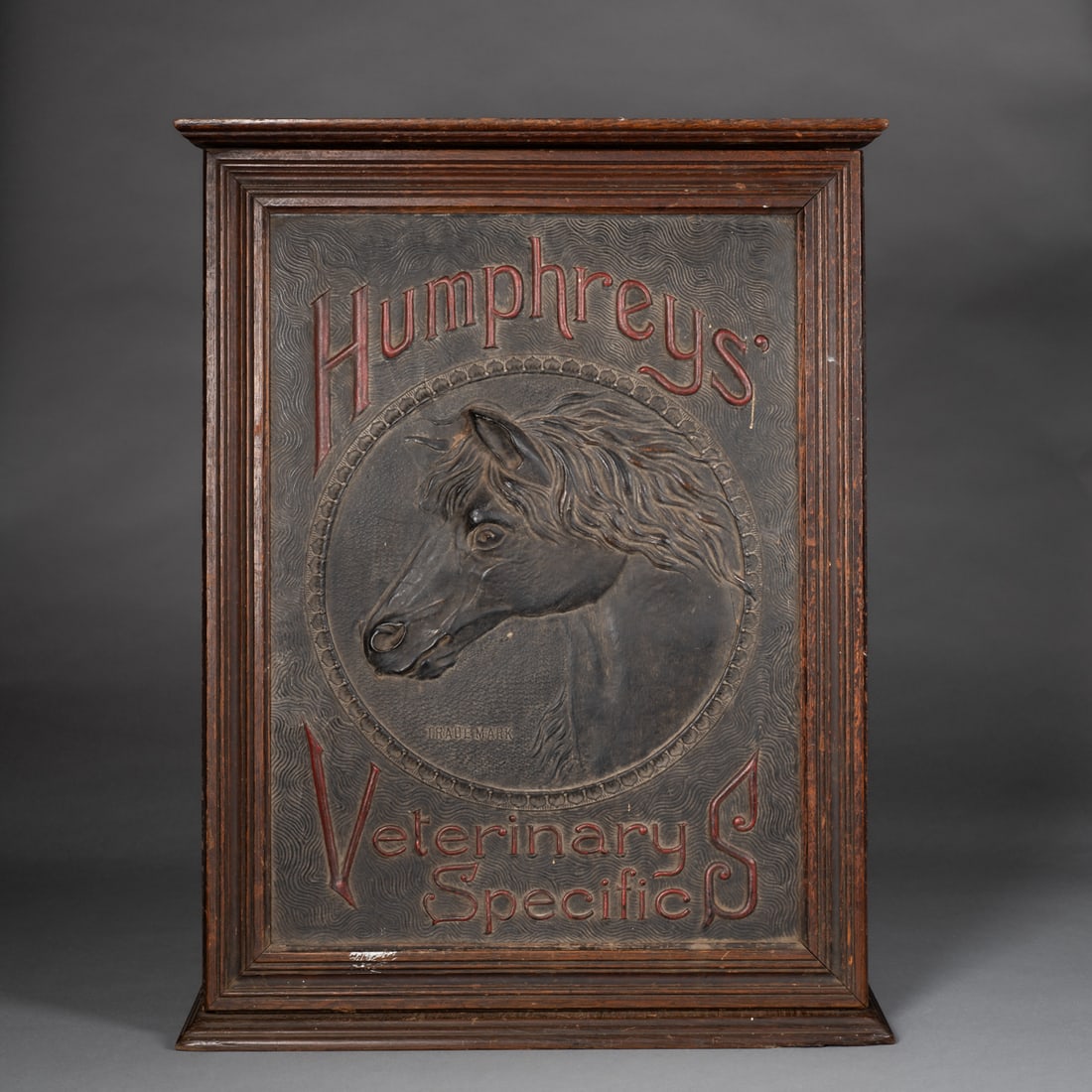 Humprey’s Veterinary cabinet: Featuring a raised molded horse head within a circular medallion and embossed red lettering on a textured field. Retains original paint and surface, with strong three-dimensional relief and bold desig