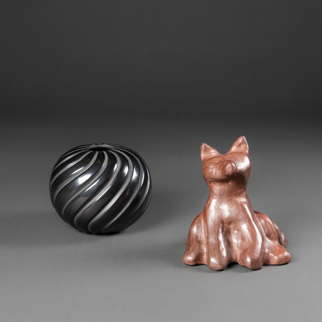 An Isleta Pueblo pottery fox and Santa Clara jar: Hand-modeled and polished clay fox figure by Diane Wade of Isleta Pueblo. The animal depicted in a reddish-brown clay, sitting poised with a large tail in back. Subtle marks highlight the handmade cha