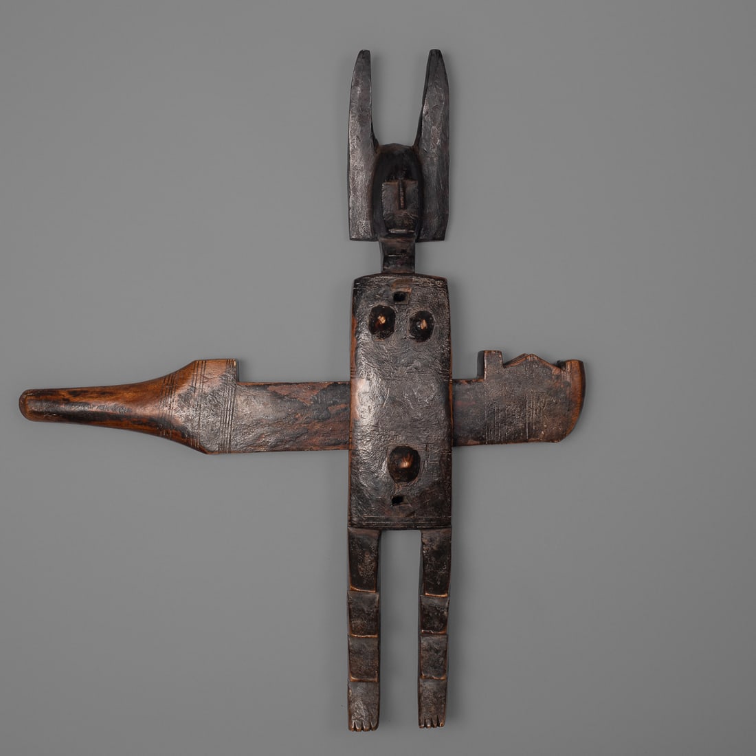A Bamana door lock: Mali, early 20th century, heavy wood door lock, standing female figure with serrated legs and incised torso and high headdress, with incised lock, overall glossy and encrusted patina. Ht. 22 1/2, wd.