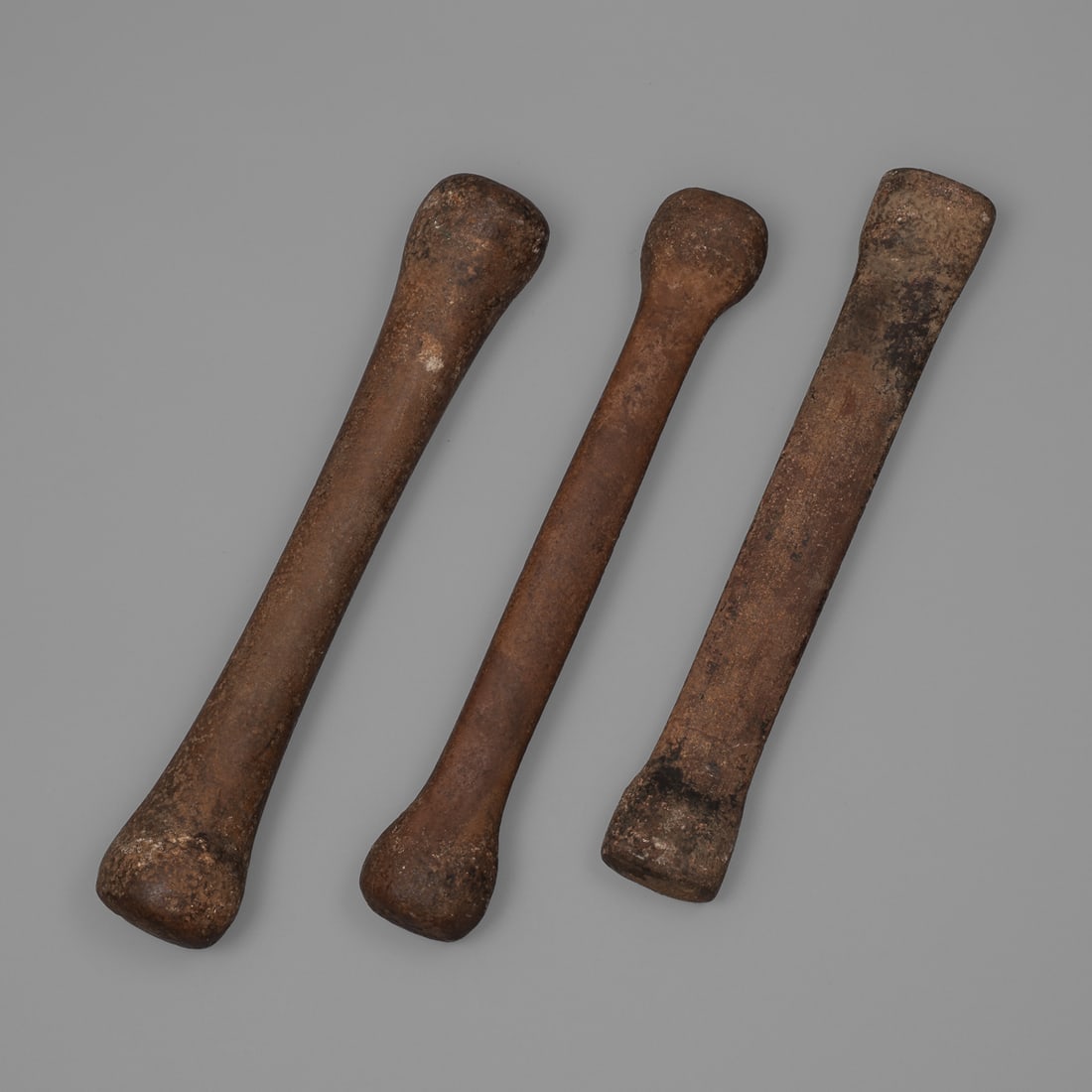 Three Dogon stone pestles: Mali, 16th-19th century, Dogon peoples pestle/grinding stones, one with a flat crossbar, the other two rounded. Lg. 15 ¾, 16 ¼, and 16 ¼ in. Provenance: The Tom Joyce Collection,