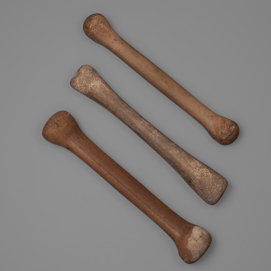 Three Dogon stone pestles: Mali, 16th-19th century, Dogon peoples pestle/grinding stones, one with a flat crossbar, the other two rounded. Lg. 16, 15 ½, and 15 1/2 in. Provenance: The Tom Joyce Collection, Santa Fe, NM.