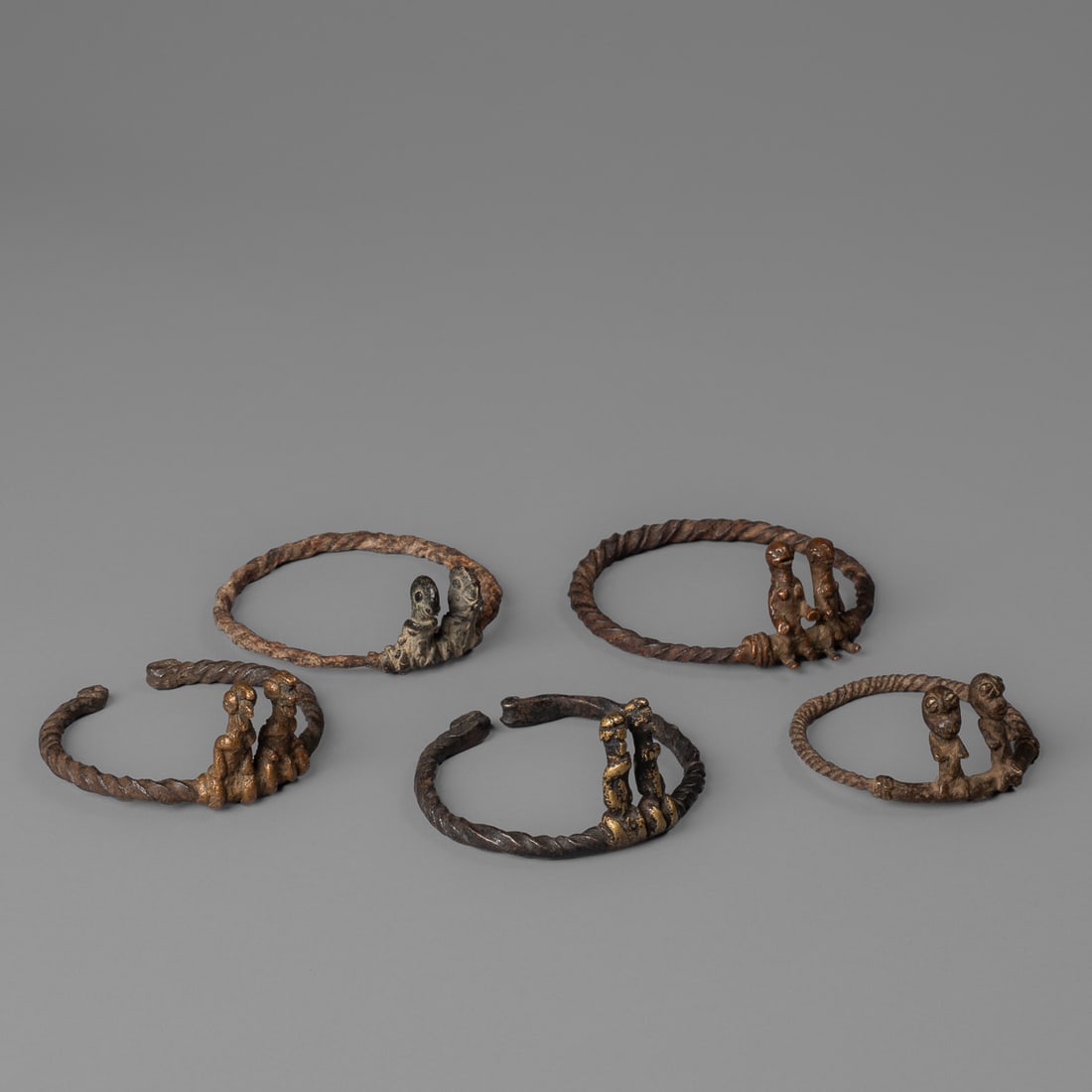 Five Lobi shrine bracelets: Burkina Faso, late 19th-early 20th century, Lobi shrine bracelets, iron and copper alloy, each twisted bracelet with two erect figures on one side, Exterior dia. 3 1/2, 3 ¼, 3, 3, and 2