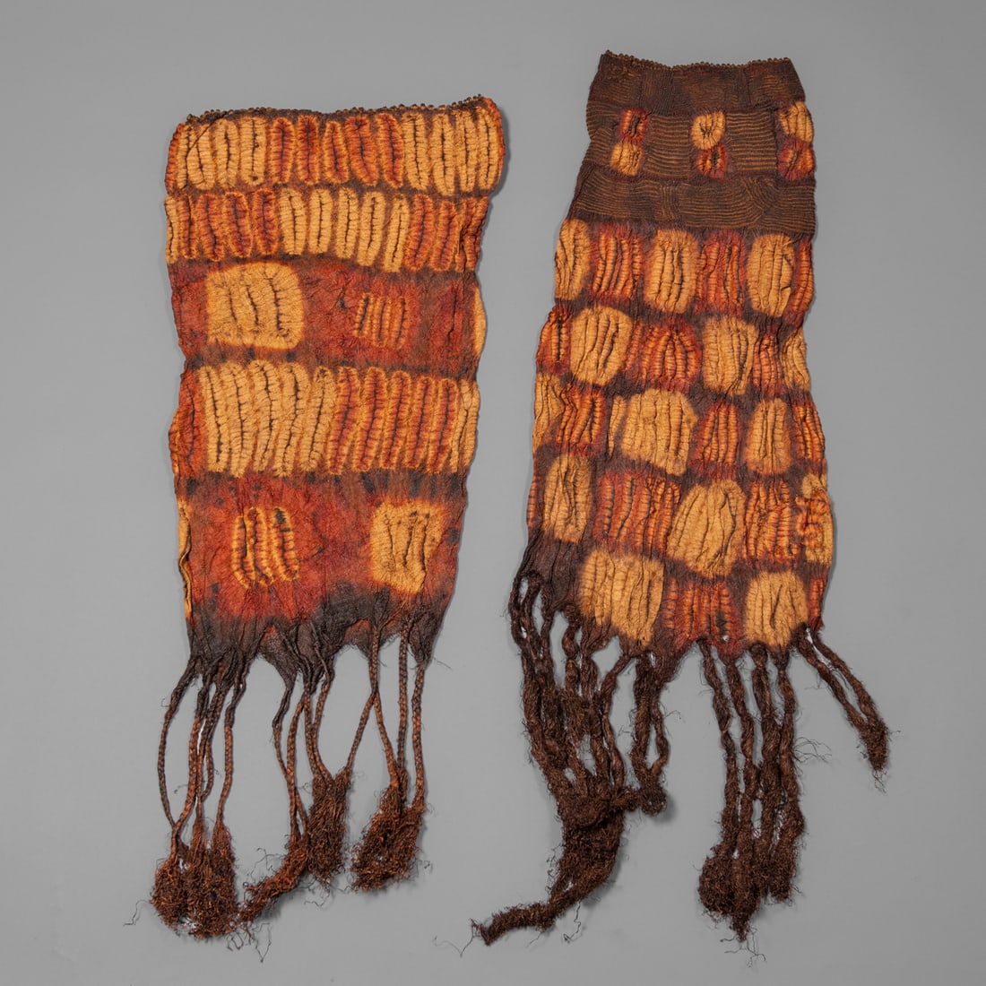 Two Dida textiles: Ivory Coast, tie-dyed, braided raffia, multicolored tubed shaped braided skirt each with long raffia tassels. Lg. including Tassel 40, wd.13 ¾, lg. including tassel 37, wd. 16 3/4 in.