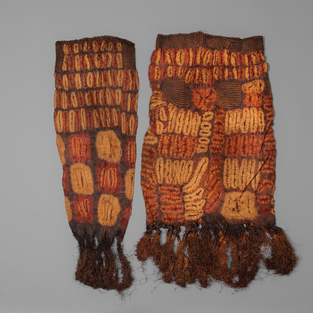 Two Dida textiles: Ivory Coast, tie-dyed, braided raffia, multicolored tubed shaped braided skirt each with long raffia tassels. Lg. including tassel 37, wd.13, lg. including tassel 47 ½, wd. 20 1/2 in.
