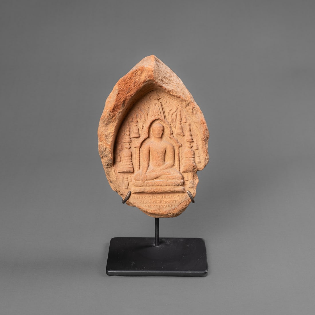 A Burmese terracotta votive: Bogan, circa 13th/14th century, terracotta a central seated Buddha with stupa forms surrounding, some areas missing, mounted on metal stand. Ht. 6 3/4, wd. 4 ½ in. Provenance: Private