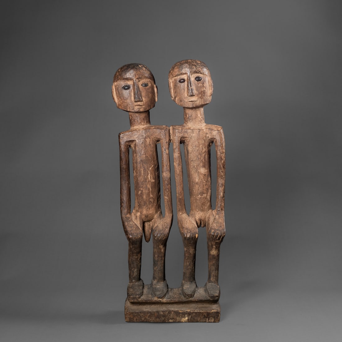 A pair of Naga figures: Konyak, the wooden male and female figures attached at shoulder, posed hands on knees on top of platform, the heads with seed eyes, encrusted patina. Ht. 19 7/8, wd. 7 1/8 in. Provenance: Private