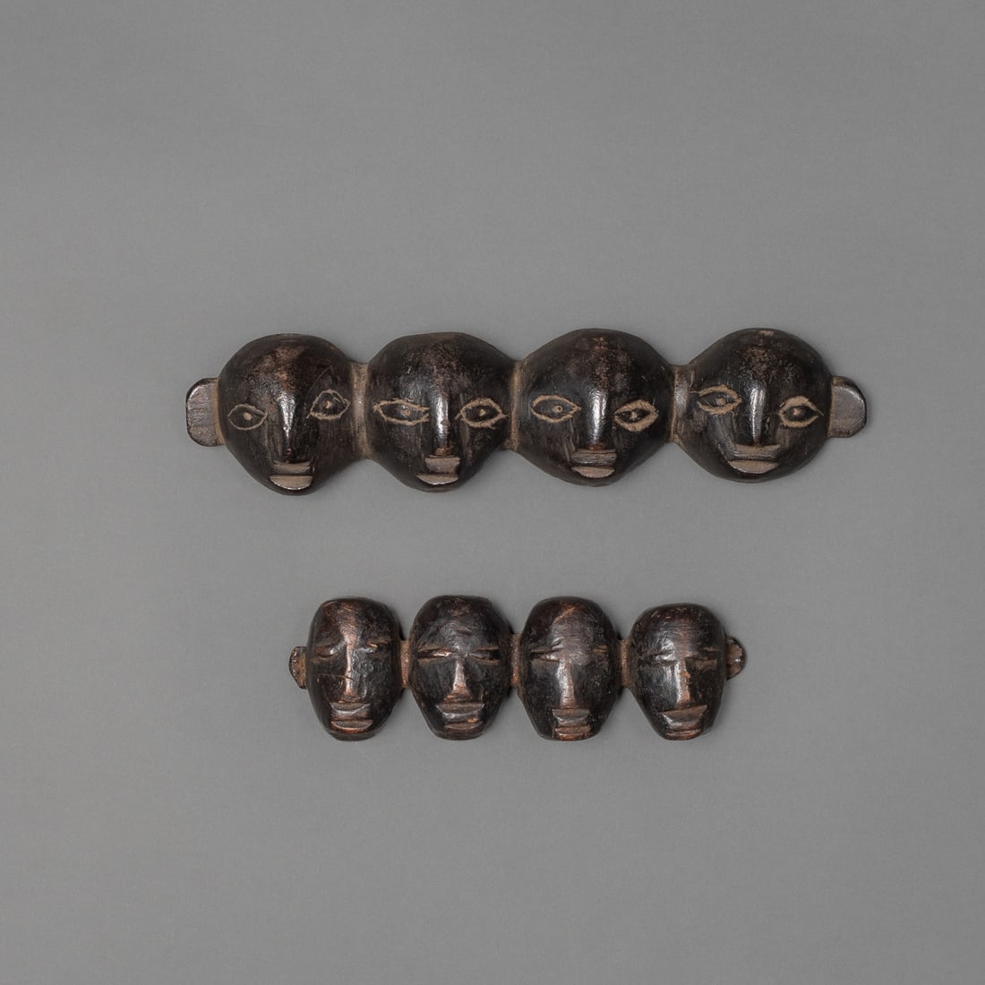 Two quad Naga head trophies: The four interlocking heads carved together with similar features, each with two holes on reverse for attachment. Lg. 7 ½, 5 in. Provenance: Private collection, Albuquerque, New Mexico.