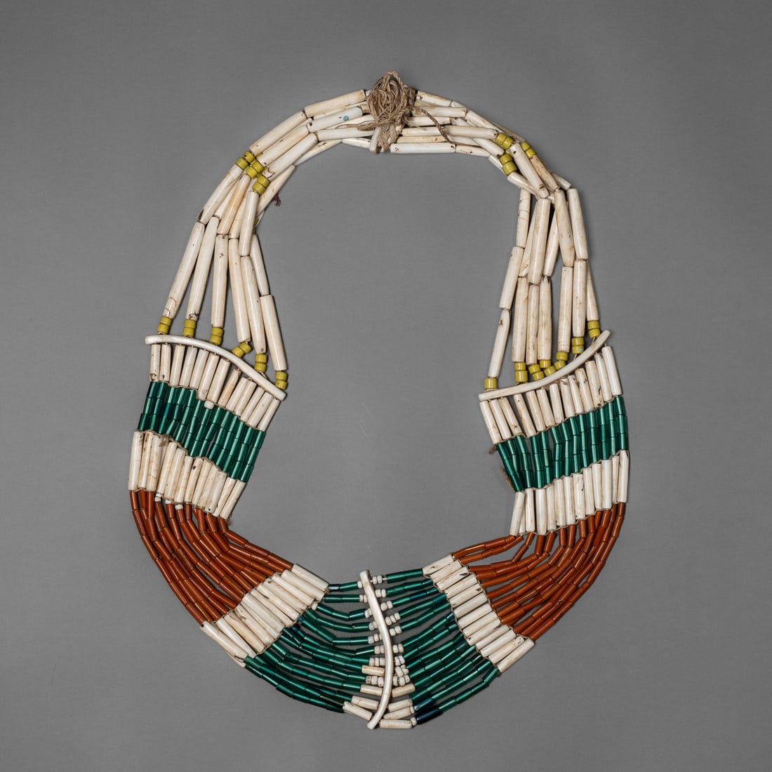 A large Naga bead necklace: Angami, the large necklace comprised of long tubular shell beads, shell spacers, and glass tubular beads, strung with cotton fiber. Lg. tied 18 ½ in. Provenance: Private collection, Albuquerque