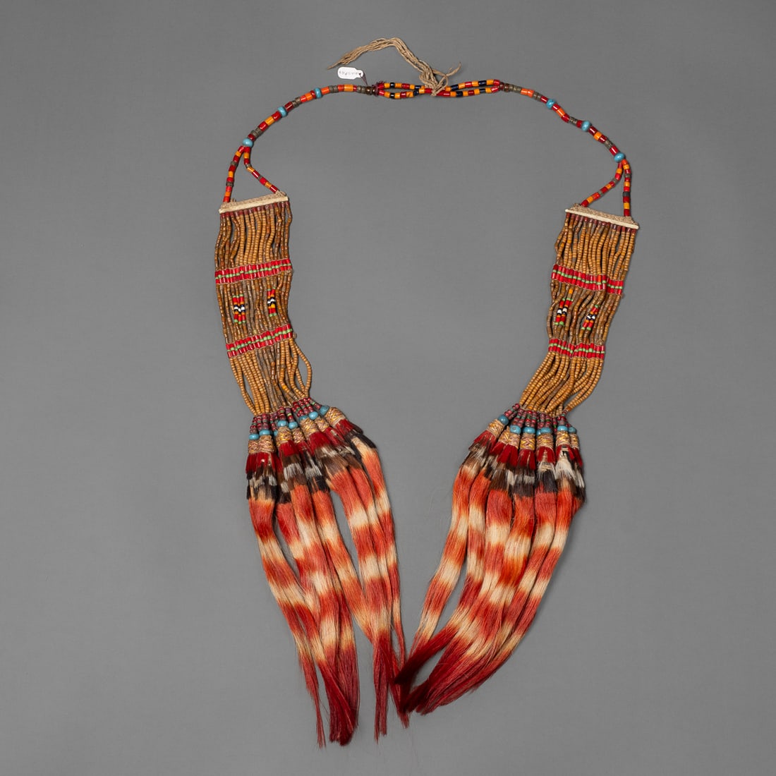 A large Naga bead and hair necklace: Konyak, multicolored large and small beads in two parts, with long dyed goat hair drops attached with rattan, overall lg. 45 ½ in. Provenance: Private collection, Albuquerque, New Mexico.