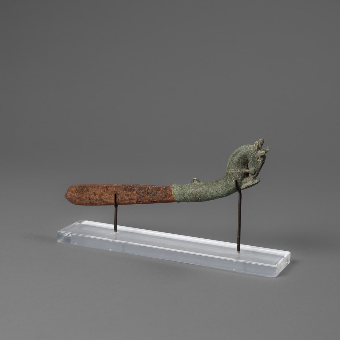 A Khmer bronze knife: South Loas, circa 14th century, the blade with a rust surface, the bronze handle with horse finial, mounted on a custom base. Lg. 7 3/4 in. Provenance: Private collection Santa Fe, NM.
