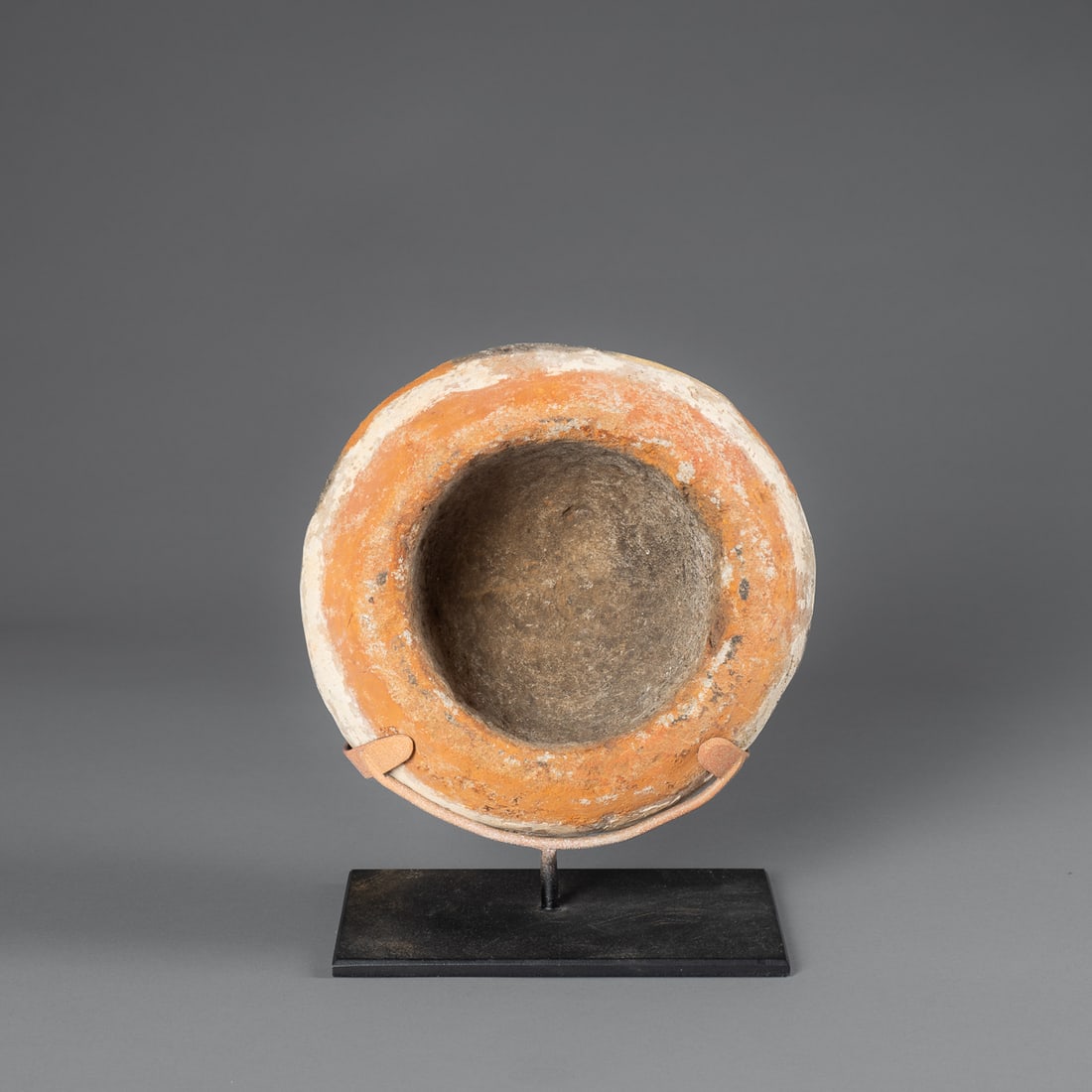 A New Guinea stone pigment mortar: Highlands, the large round stone, hollowed out with a painted exterior in natural pigments, mounted on a metal stand. Ht. 3 1/2, wd. 6 3/4 in. Provenance: Private collection Santa Fe, NM.