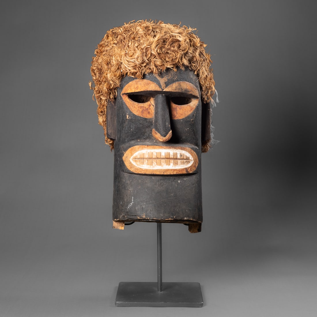 A New Ireland wood mask: Northern New Ireland, Tabar Islands, circa 1920s/30’s, the hollowed out elongated head with cut out eyes, heavy brow, and open mouth with teeth below the large nose, with blackened pigment, white