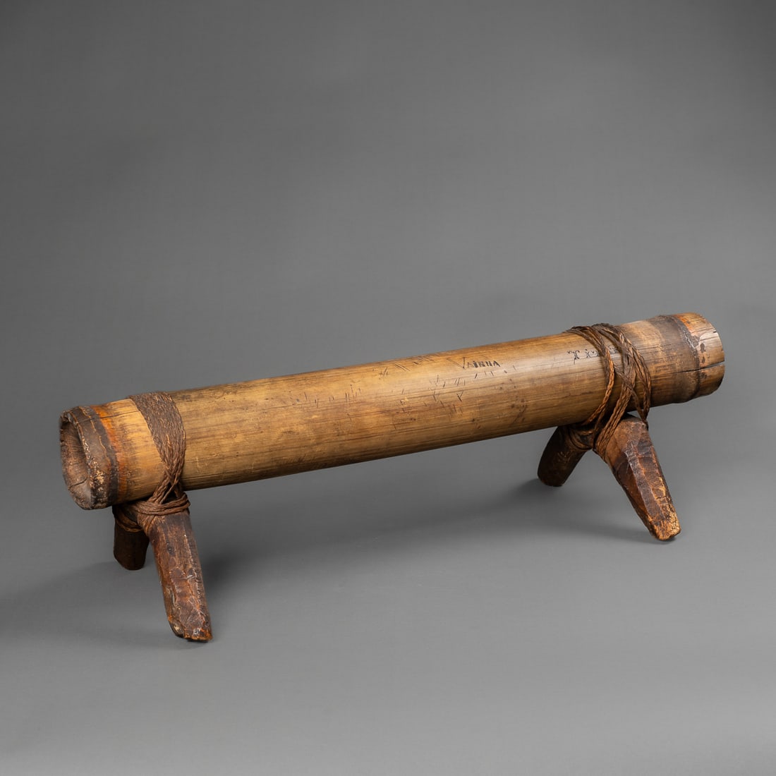 A Fijian neck rest: 19th century, the large bamboo pillow inscribed with three names, with two wooden legs attached, with sinnet. Ht. 6, lg. 21 ¼ in. Provenance: Private collection Santa Fe, NM.