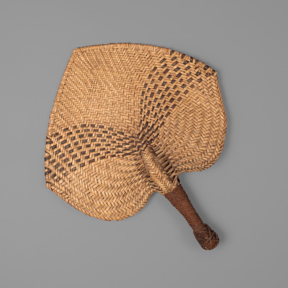 A Fijian fan, i iri: 19th century, made from young coconut leaf with a senet handle, the standard ace of spade shape with traditional patterns of black arcs radiating from the base of the handle to the sides of the fan. L