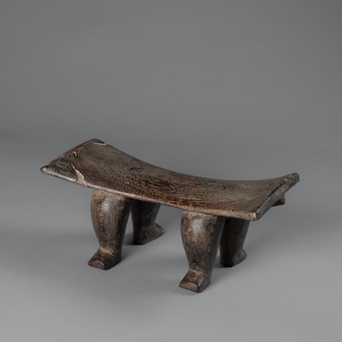A Futuna Island neckrest: Late 19th century, carved from palm wood, the wide, curved pillow standing on four squat legs with square-cut feet, minor wood loss. Ht. 5 1/2, lg. 12 1/2 in. Provenance: Private Collection, Santa