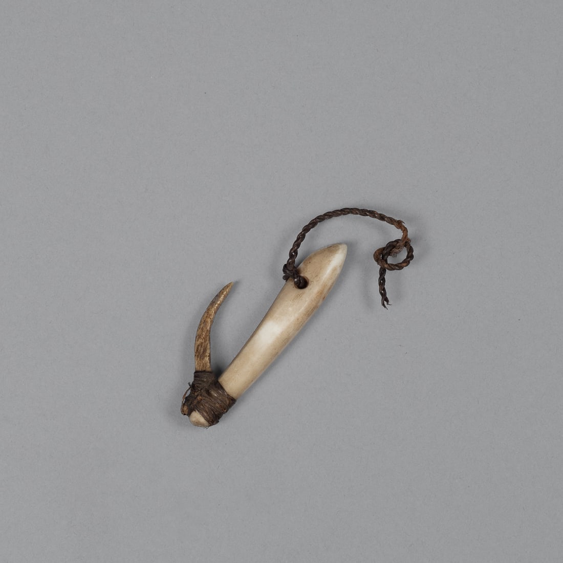 A Micronesian stone and bone fishing lure: A rare 19th century fishing lure from Micronesia, constructed from stone and bone. The lure retains a portion of its original fishing line, made of sennit — cordage twisted from coconut fiber. Measu