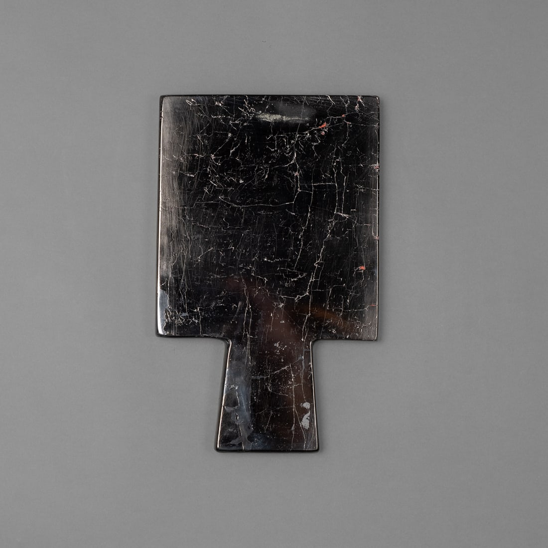 A Pre-Columbian Chavin mirror: Circa 400 B.C., an anthracite mirror, with heavy smooth black rectangular body and rhombus handle, shiny black patina to show reflection. Ht. 7 1/2, wd. 4 5/8 in. Provenance: Private collection,