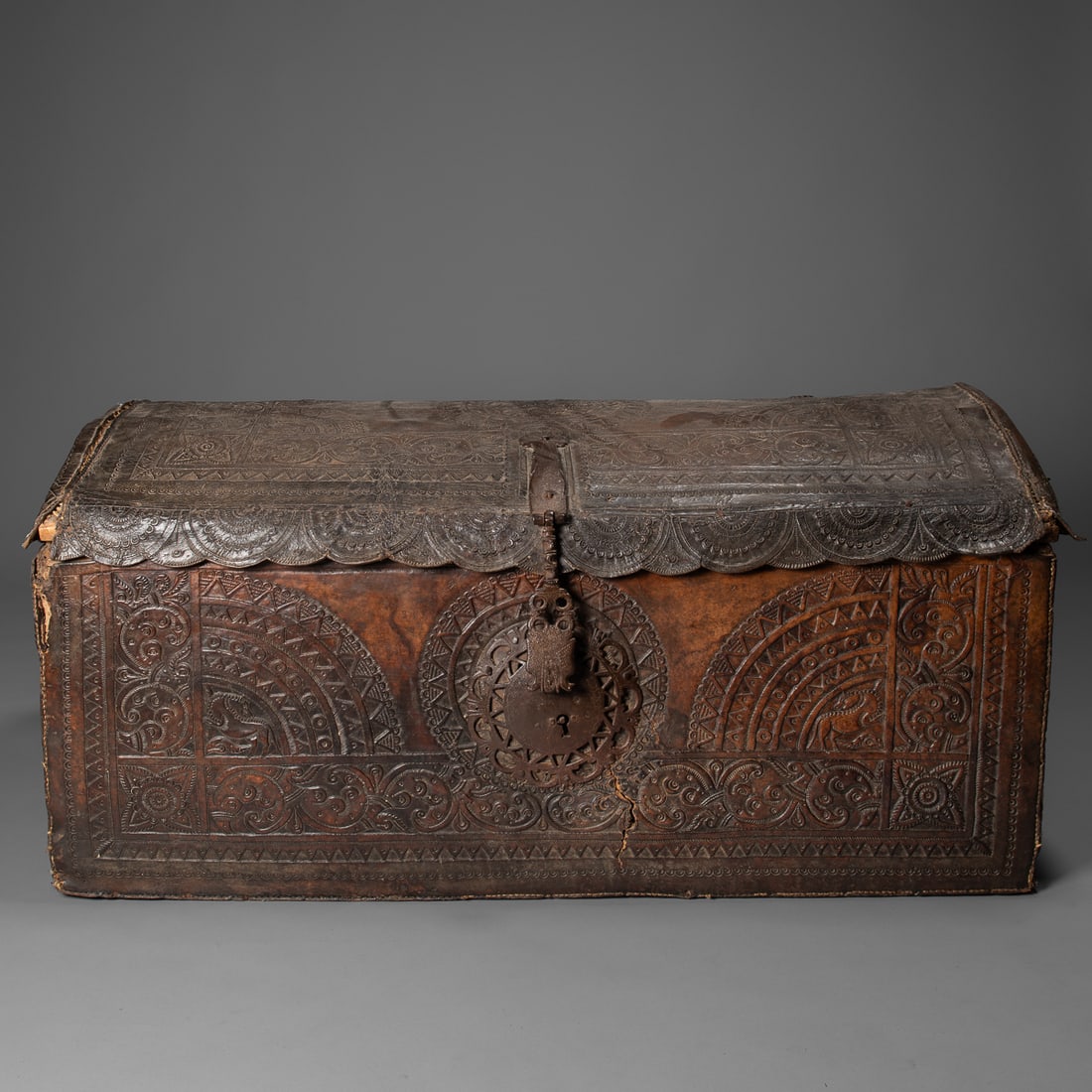 A 17th century Spanish colonial travelling chest: 17th century, Puebla, Mexico, the wooden frame entirely covered in embossed leather, richly decorated with scrollwork, stylized foliage, symbols of power and authority prevalent in Spanish