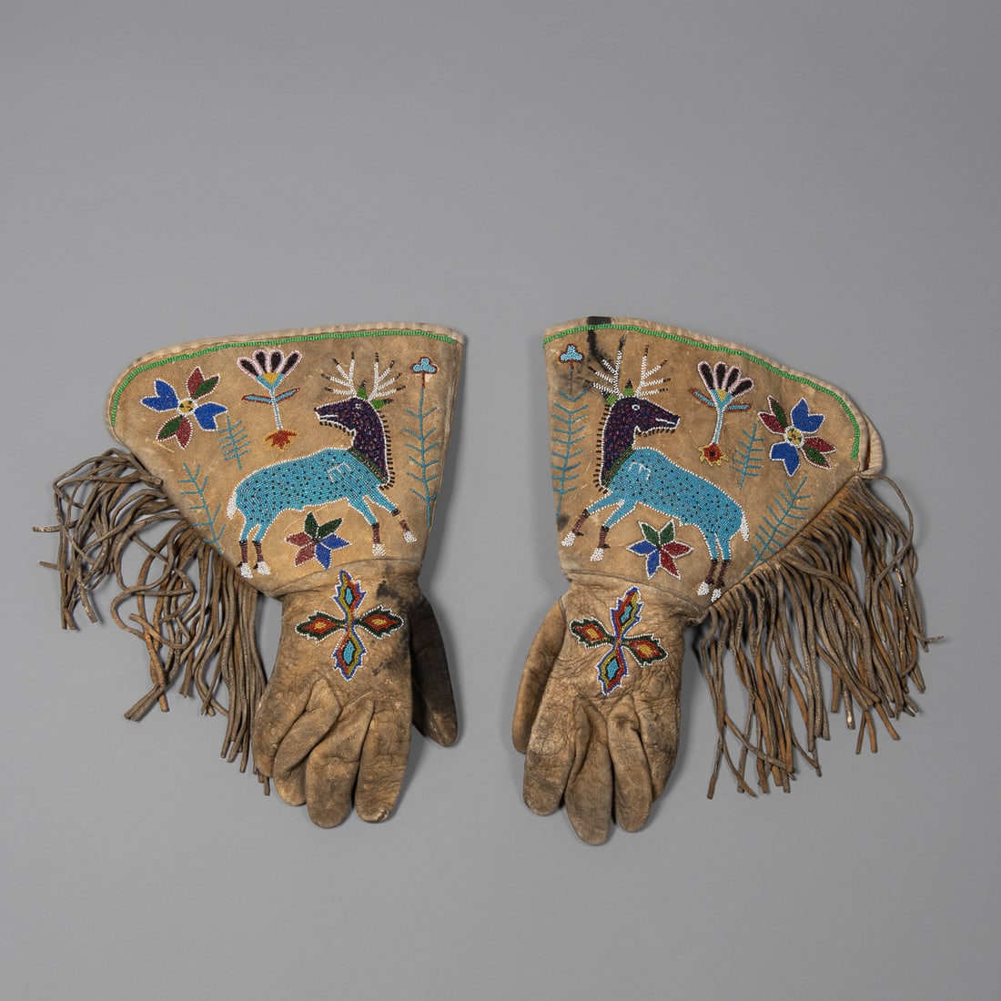 A pair of Elk pictorial beaded gauntlets: Plateau or Great Basin, fourth quarter 19th century, pictorial gauntlets with steel cut beads, with red cotton lining, (minor ink stains). Size 10 x 14 in.