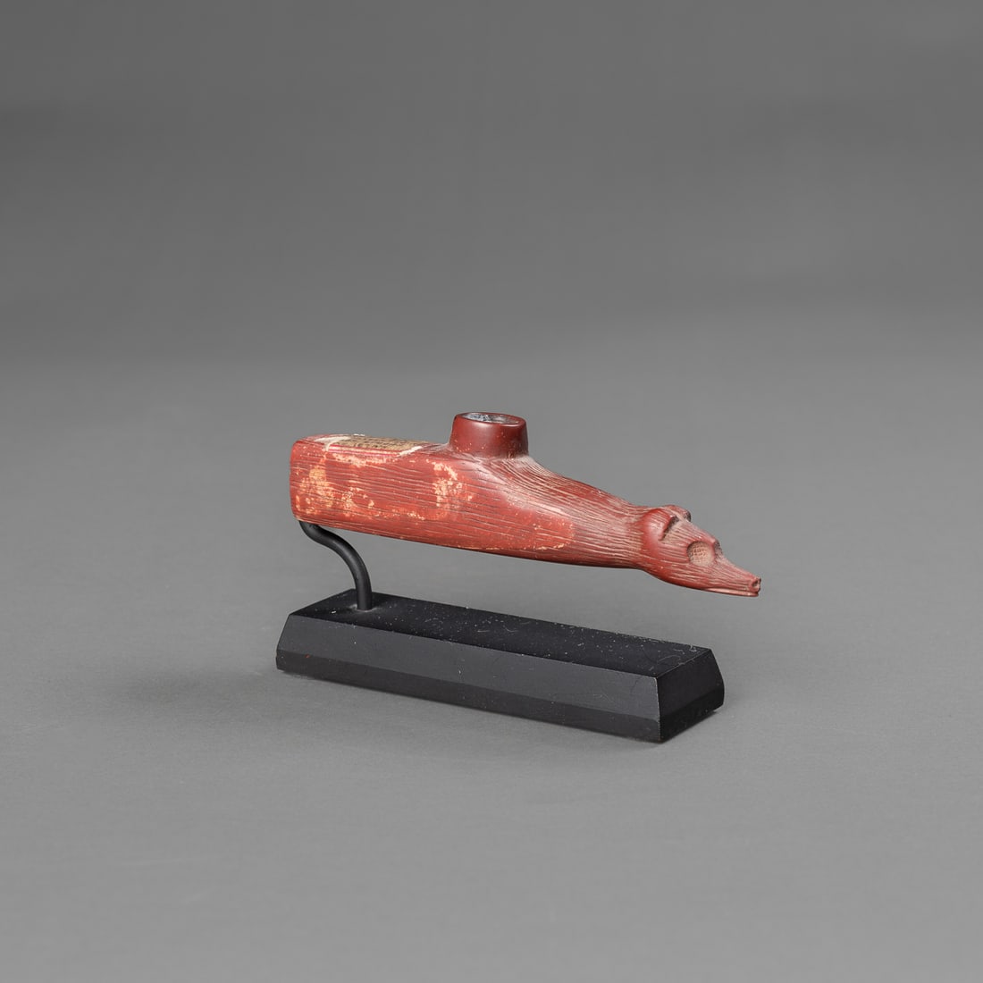 A Plains effigy pipe bowl: Crow, Northern Plains, fourth quarter 19th century, the red pipe incised with detailed lines, the end of the pipe with animal figural head, two rounded ears, eye sockets, and pointed snout with nose