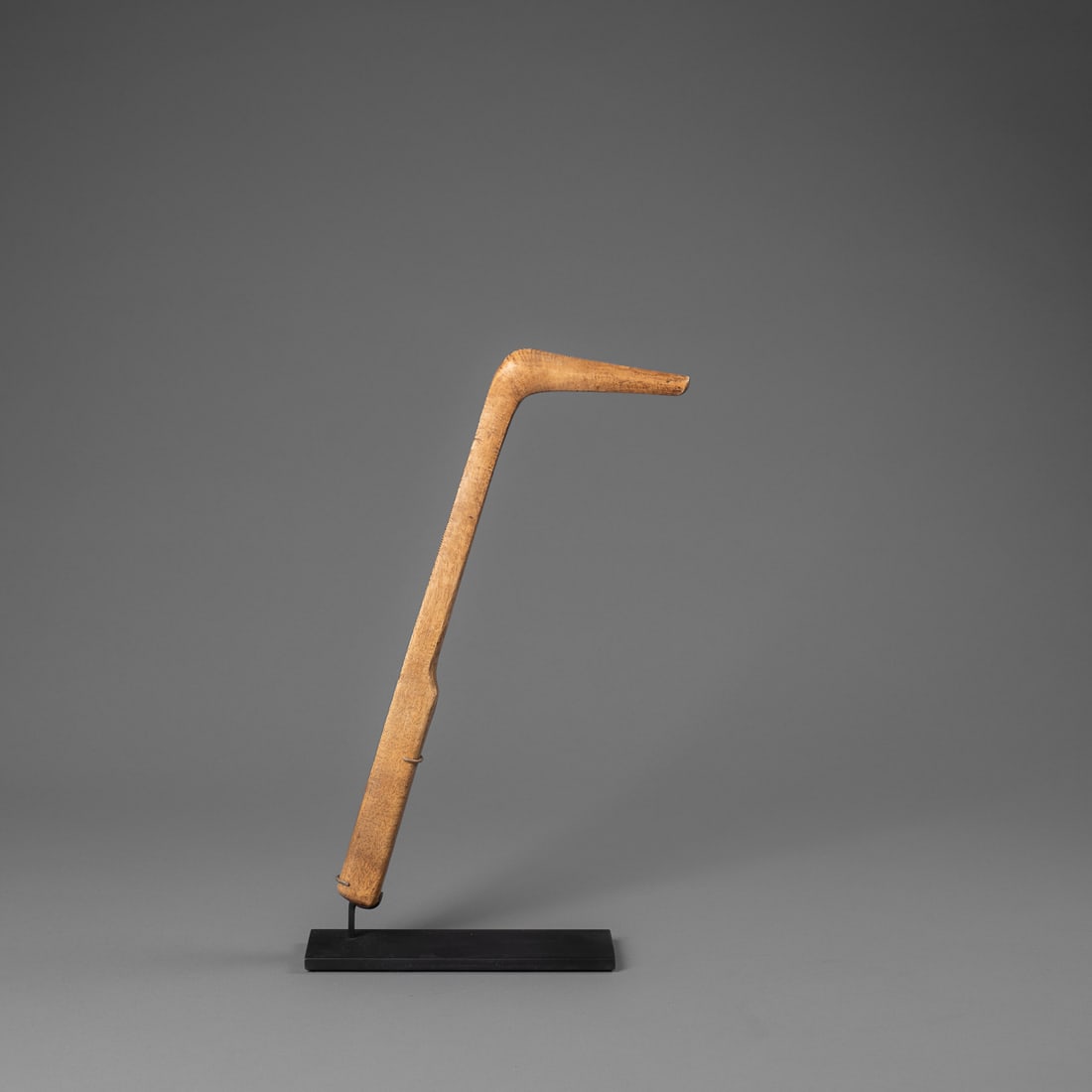 A Potawatomie effigy drum beater: Circa 1860s, a wooden drum beater, the head of which is carved to resemble an abstracted loon, with custom metal stand. Ht. 11 1/2, lg. 4 in. Provenance: The James Pavitt and Carolyn Stettner
