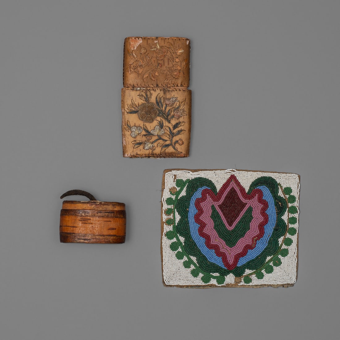 A lot of three Woodlands native objects: The beadwork panel in two different greens, blue, red, and pink on a white ground, Ht. 5, wd. 6 in. The larger bark container with floral embroidery on the exterior, on both sides, with some