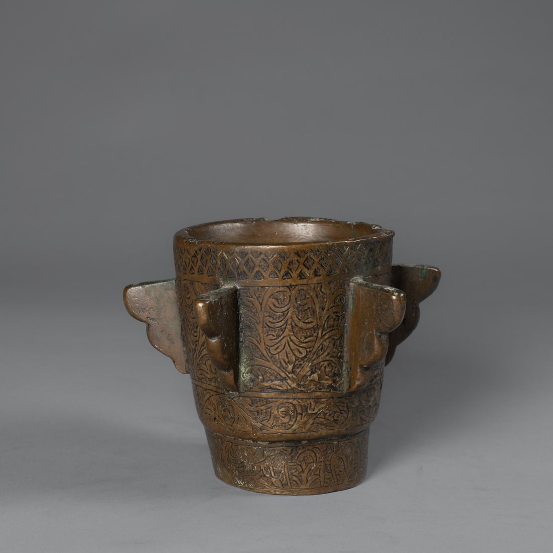 A Spanish Moorish bronze mortar: 19th century, the heavy bronze mortar fully decorated on the exterior with incised foliate designs, with five projections around the sides. Ht. 5, wd. 4 1/2 in. Provenance: Private Collection, Santa