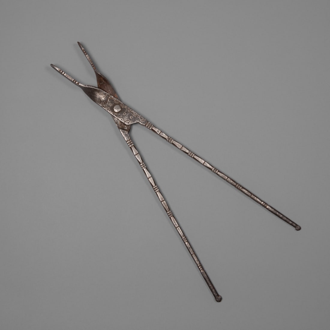 A pair of Spanish Colonial ember tongs: Spanish Colonial/New Mexican/Puebloan, the long iron tongs decorated with stamped and chisel designs. Lg. 21 ½ in. Provenance: The Tom Joyce Collection, Santa Fe, NM; The Robert LeMunyon