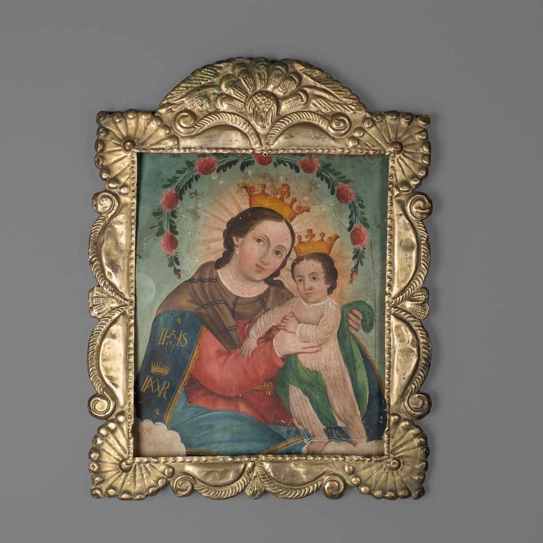 A Mexican tin/nickel frame: The tin/nickel frame attached to a wood back frame, with foliate designs, with a painting of the Madonna and Child on tin. Size of frame 16 x 12, size of painting 11 x 9 1/4 in. Provenance: Private