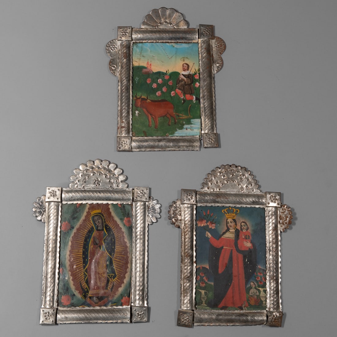 Three New Mexican tin frames: Three tin frames, each with paintings on tin, one of the Madonna and two of Saints, (minor damage to the frames in places). Frame size 14 1/2 x 11 3/4, size of paintings 9 3/4 x 6 3/4 in. Provenance: